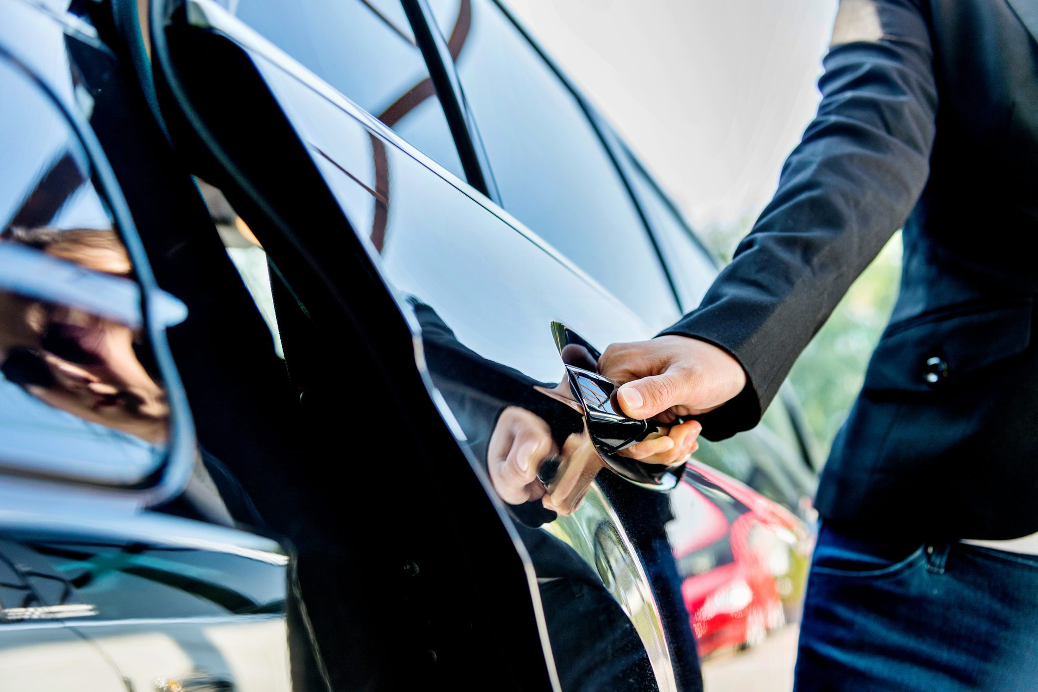 A person unlocking a black car with a key.