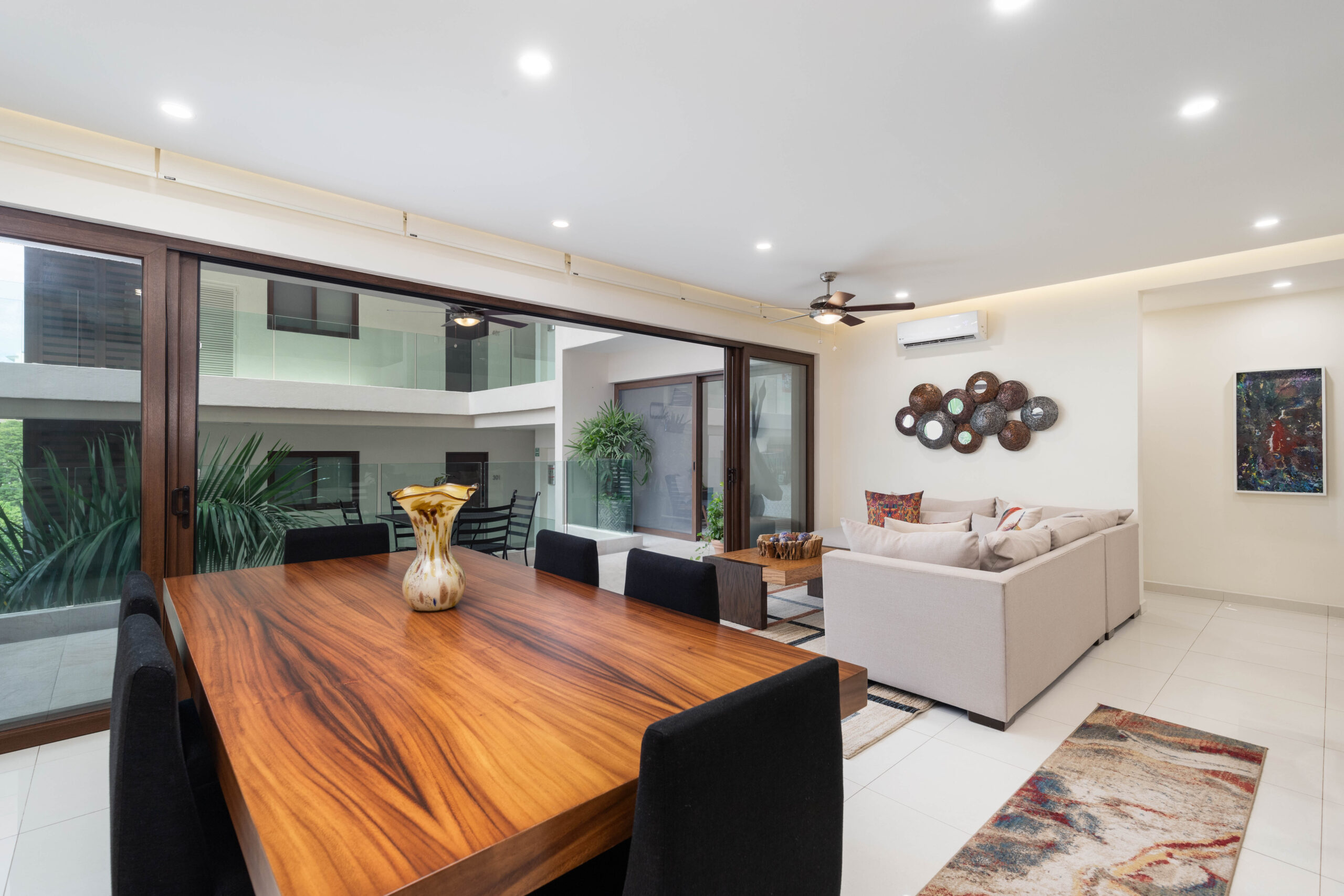 Modern living room with wooden dining table and large glass doors.