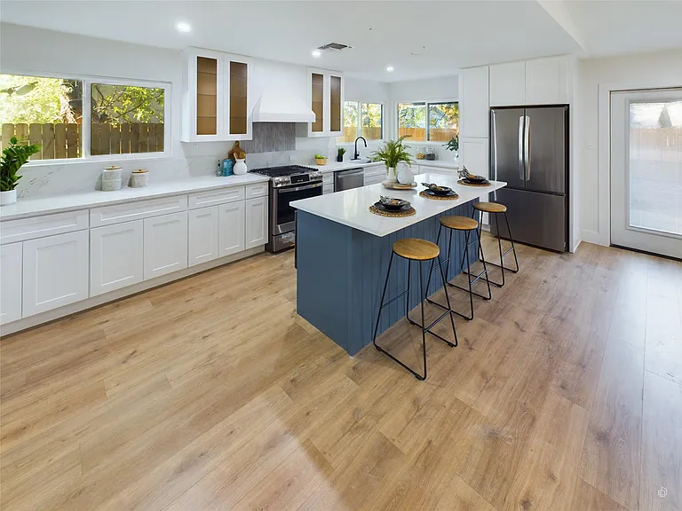 Modern kitchen with white cabinets and a blue island with stools.