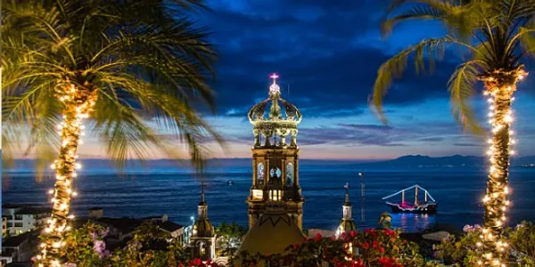 Illuminated tower against a twilight sky by the sea.