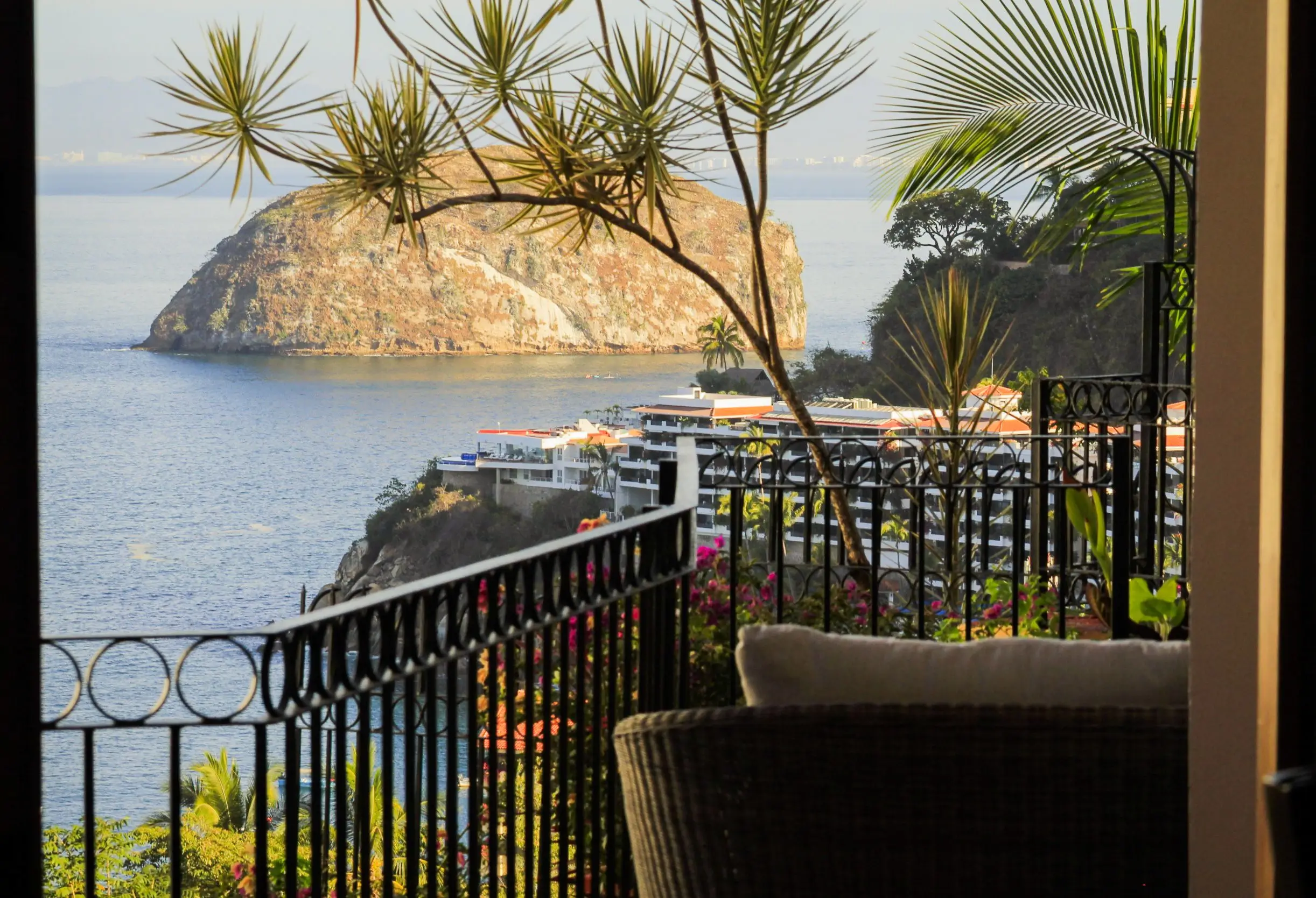 Scenic balcony view overlooking calm waters and rocky islands during sunset.