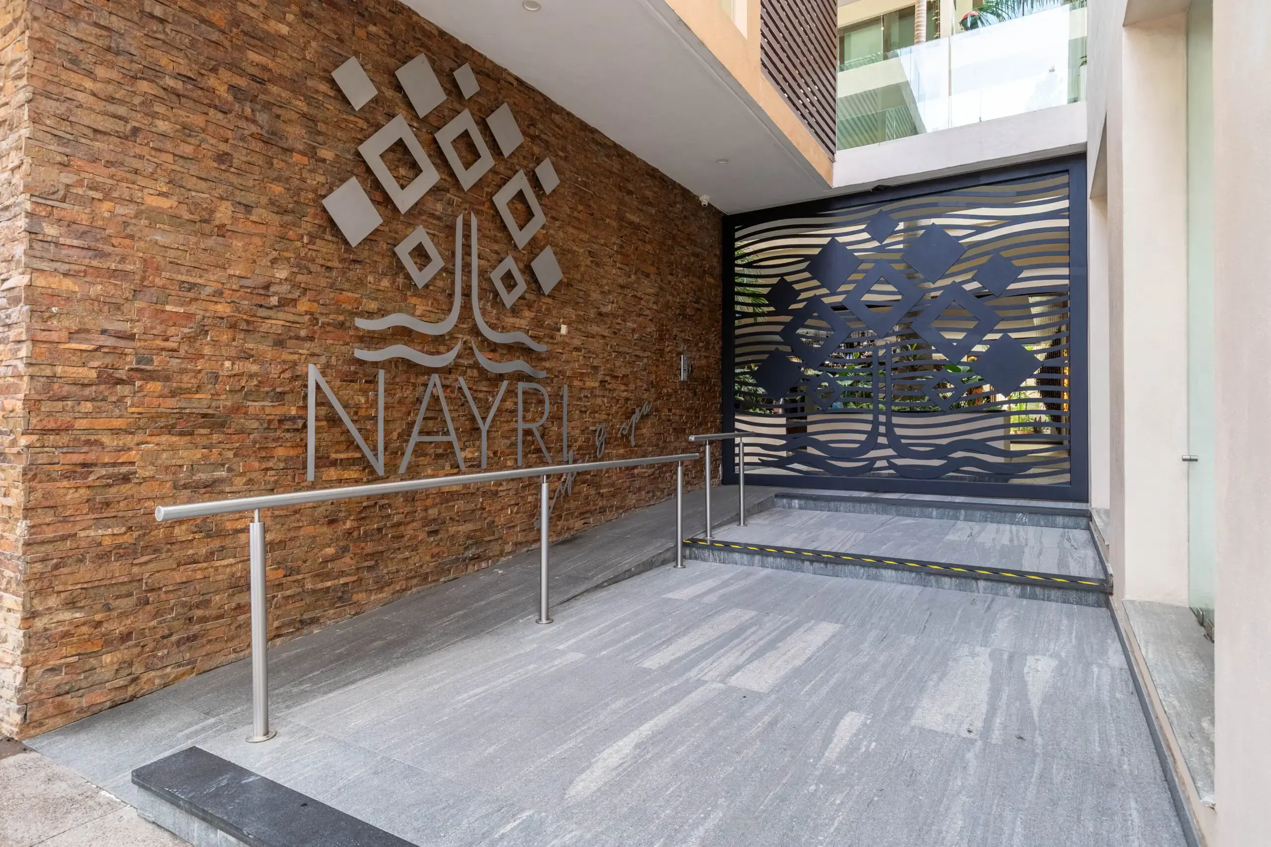 Entrance of Nayar residence with modern brick wall and metal gate.
