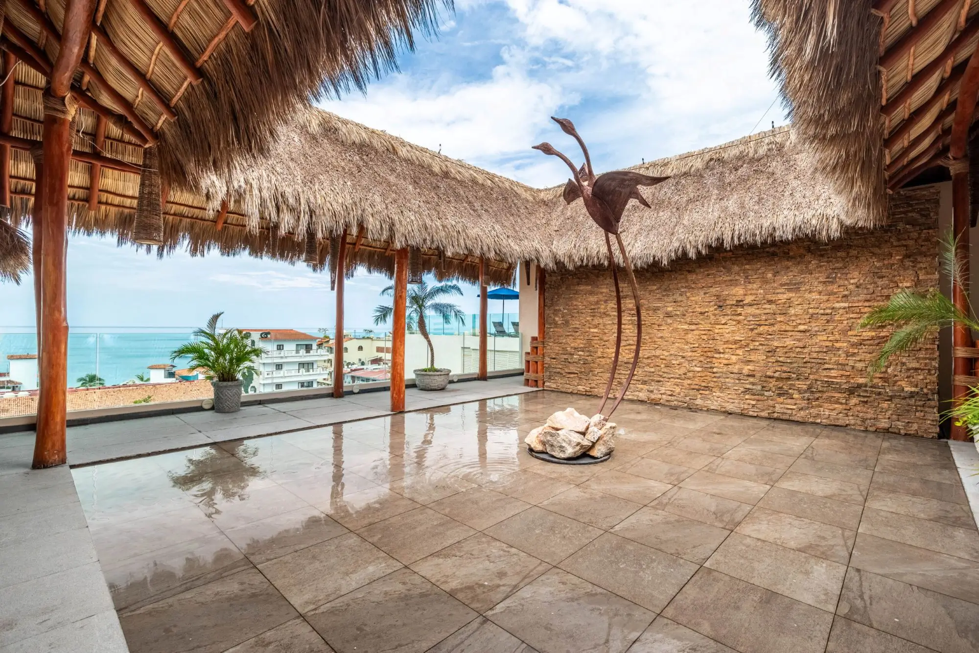 Tropical beach hut with a hanging bird sculpture and ocean view.